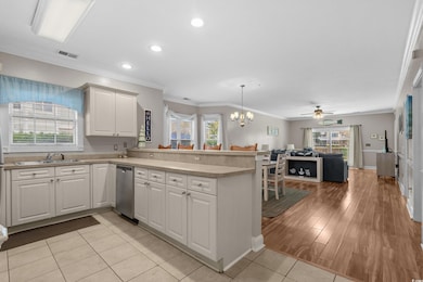 Kitchen with crown molding, hanging light fixtures, a chandelier, a peninsula, and open floor plan