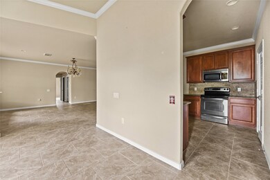 Explore a modern kitchen equipped with stainless steel appliances and rich wood cabinetry, seamlessly connected to a spacious living area with elegant tile flooring.