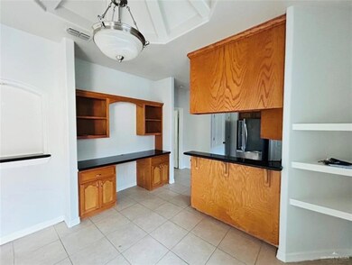 Kitchen with open shelves, fridge, dark countertops, light tile patterned floors, and brown cabinets