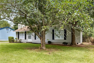 View of property hidden behind natural elements featuring a front yard