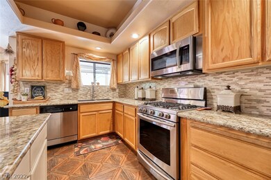 Upgraded kitchen with backsplash, tile floors, modern appliances, and ample storage space