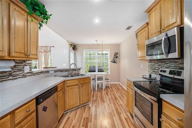 Kitchen featuring tasteful backsplash, stainless steel appliances, light wood-style floors, and light countertops
