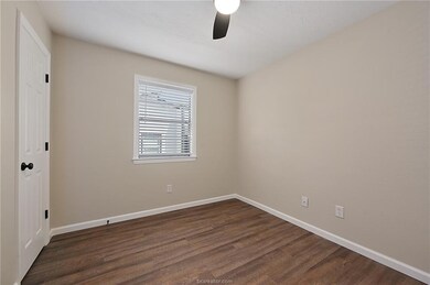 Unfurnished room featuring ceiling fan and dark ha