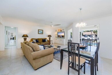 Living area with light tile patterned floors, crown molding, and ceiling fan with notable chandelier