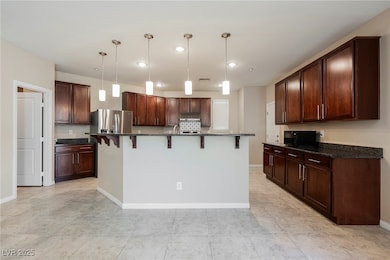 Kitchen with a kitchen bar, dark stone counters, recessed lighting, and pendant lighting