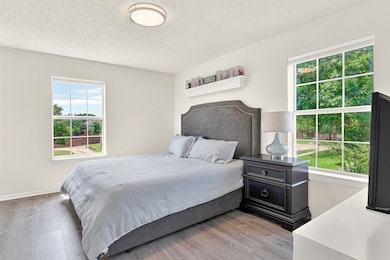 Bedroom with light wood-style floors and a textured ceiling
