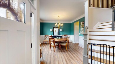 Dining room featuring stairway, wood finished floors, crown molding, wainscoting, and a chandelier