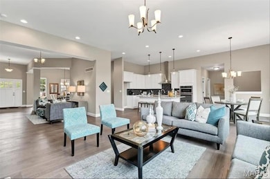 Living area with a chandelier, wood finished floors, and recessed lighting