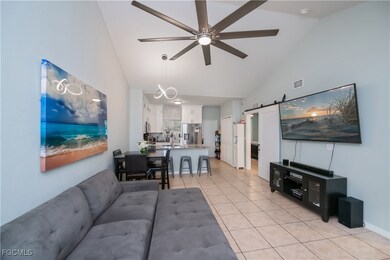 Living area with a barn door, light tile patterned floors, high vaulted ceiling, and a ceiling fan