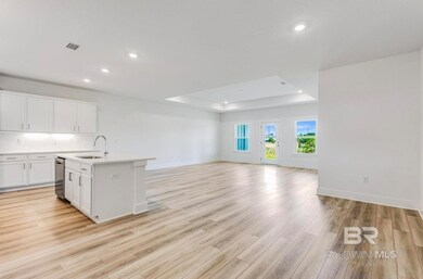 Kitchen featuring a tray ceiling, white cabinets, an island with sink, sink, and light hardwood / wood-style floors