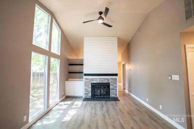 Unfurnished living room with high vaulted ceiling, a ceiling fan, light wood-type flooring, a textured ceiling, and a fireplace