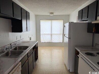 Kitchen featuring dark cabinets, white appliances,