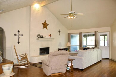Living room with ceiling fan, a fireplace, and high vaulted ceiling