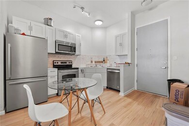 Kitchen with appliances with stainless steel finishes, light wood-style floors, decorative backsplash, and light countertops