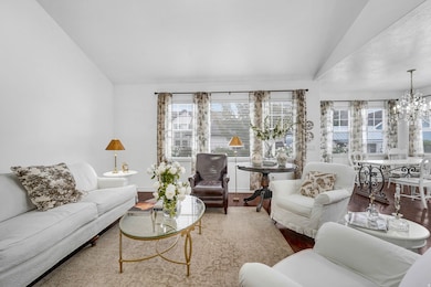 Living area with vaulted ceiling, wood finished floors, and a chandelier
