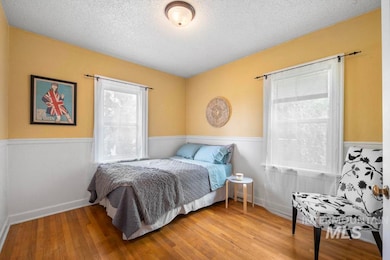 Bedroom featuring wainscoting, wood finished floors, and a textured ceiling