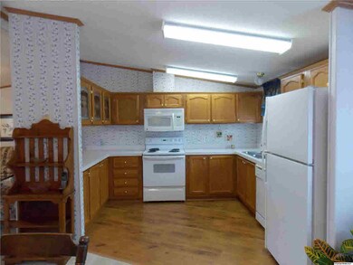Kitchen features oak cabinets, range, built in microwave and refrigerator.
