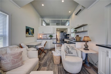 Living room with dark wood-type flooring, a wall m