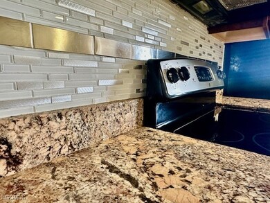 Kitchen featuring light stone counters, decorative backsplash, and electric stove