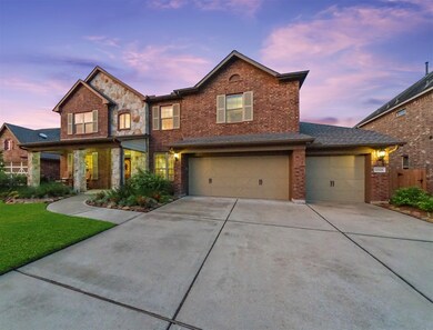 Gorgeous elevation with stone columned front porch and three car garage. Lush lawn with pair of live oaks.