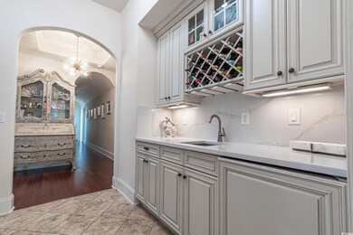 Bar area featuring arched walkways, light stone countertops, glass insert cabinets, a chandelier, and light tile patterned floors