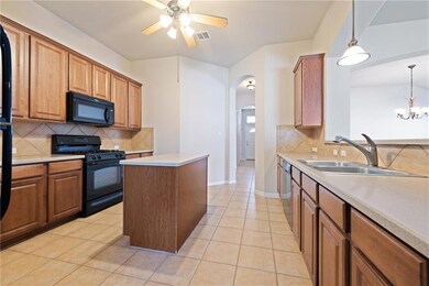 Kitchen featuring black appliances, arched walkwa
