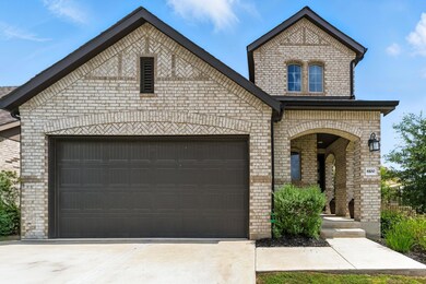 French country home featuring brick siding, concr