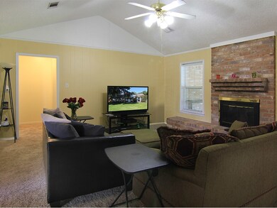 Living room offers tons of natural lighting coming from front & back windows, seating area along the wood burning fireplace, high vaulted ceilings, access into the hallway that leads to bedrooms.