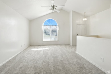 Carpeted empty room featuring lofted ceiling and a ceiling fan