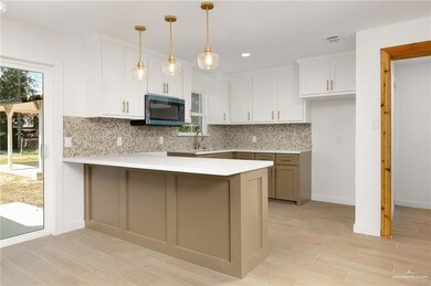 Kitchen featuring a peninsula, white cabinetry, backsplash, and visible vents