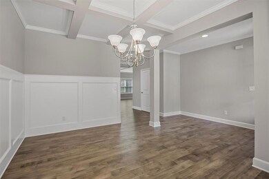 Unfurnished dining area with coffered ceiling, a chandelier, beamed ceiling, a decorative wall, and dark wood finished floors