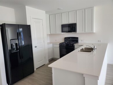 Kitchen with a sink, black appliances, light wood-
