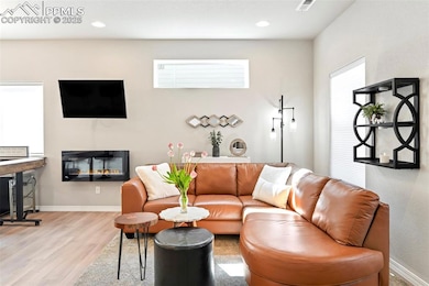Living area with wood finished floors, baseboards, and recessed lighting