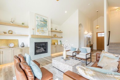 Living area with a tile fireplace, high vaulted ceiling, wood finished floors, arched walkways, and stairway