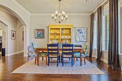 Dining room featuring ornamental molding, a chandelier, dark wood-style floors, and arched walkways
