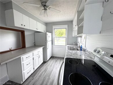 Kitchen featuring range with electric cooktop, ceiling fan, white cabinets, sink, and light wood-type flooring