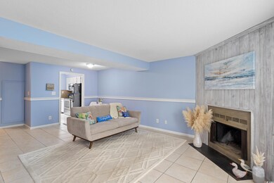 Living area featuring light tile patterned flooring, wood walls, an accent wall, baseboards, and a fireplace with flush hearth