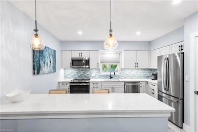 Kitchen featuring a sink, stainless steel appliances, light stone counters, and decorative backsplash