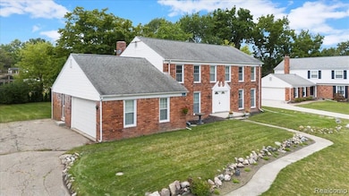 Colonial home with a front lawn, brick siding, roof with shingles, asphalt driveway, and a garage