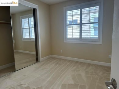 Unfurnished bedroom featuring multiple windows, light colored carpet, and a closet