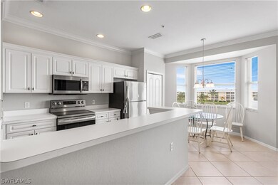 Kitchen with white cabinetry, appliances with stai