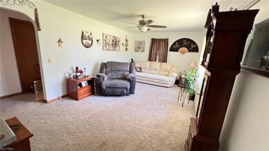 Spacious living room has newer ceiling fan, carpet