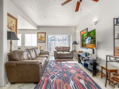 Living room with a textured ceiling, plenty of natural light, and a ceiling fan