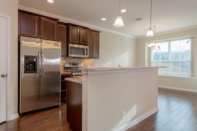 Kitchen featuring stainless steel appliances, tasteful backsplash, ornamental molding, dark brown cabinets, and dark wood-style flooring
