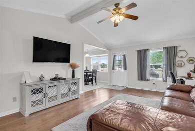 Living room with crown molding, hardwood / wood-style floors, vaulted ceiling with beams, ceiling fan, and a textured ceiling