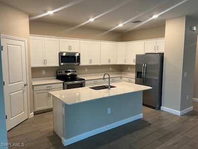 Kitchen with white cabinets, sink, appliances with