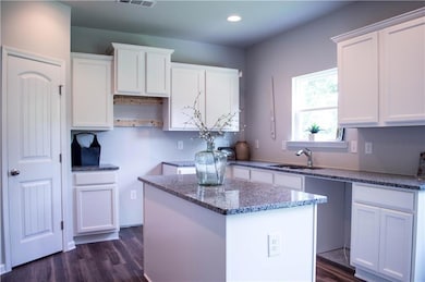 Kitchen with stone countertops, white cabinets, a 