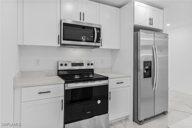 Kitchen with light stone counters, white cabinetry