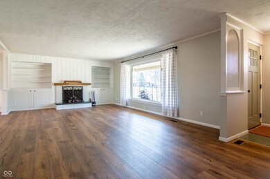 unfurnished living room featuring hardwood / wood-style floors, built in features, baseboards, a textured ceiling, and a brick fireplace