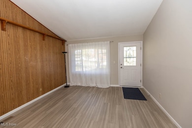 Entryway with plenty of natural light, light wood-style floors, lofted ceiling, and wood walls